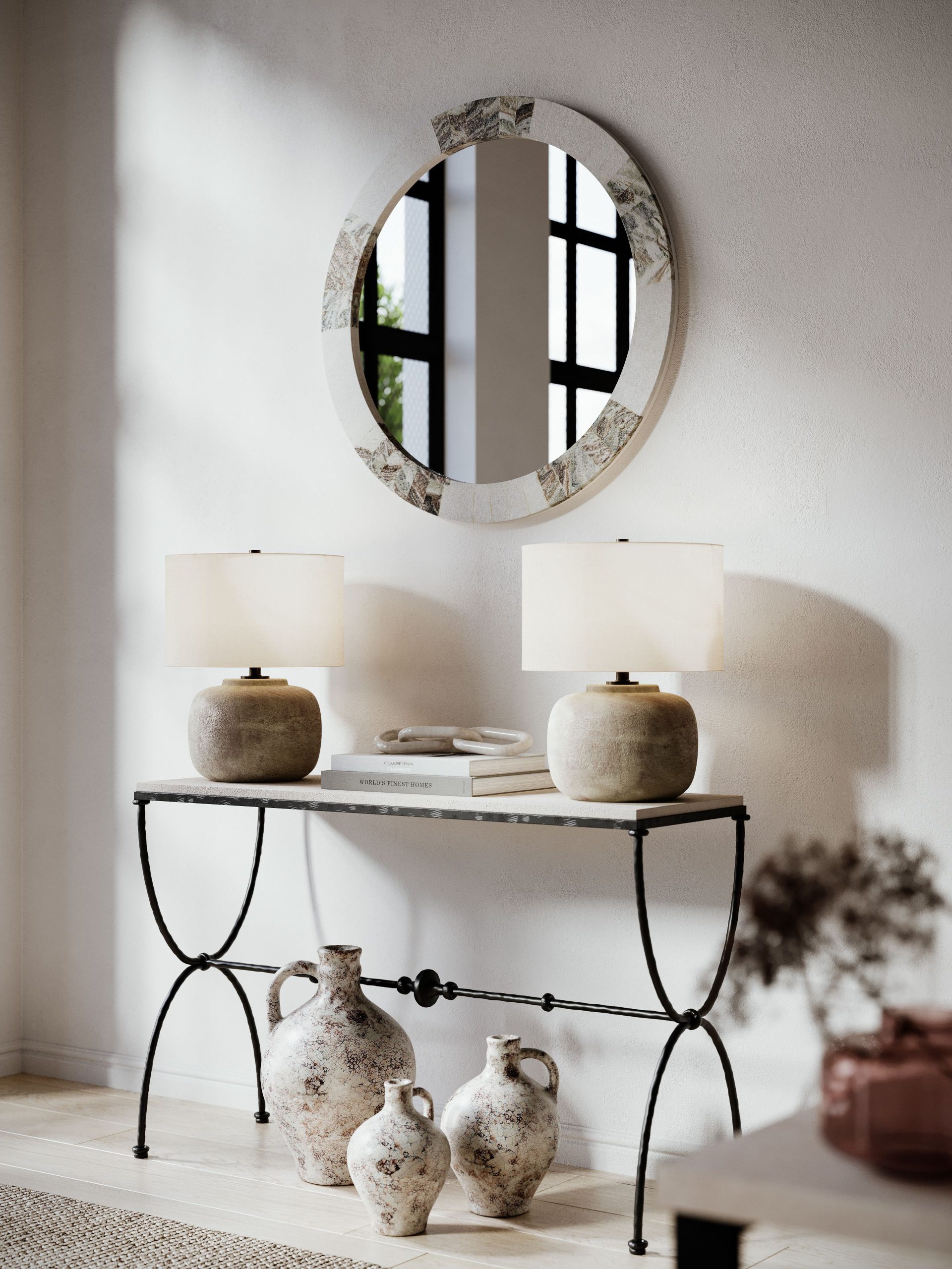 3D rendering of a wrought iron console table with ceramic table lamps, round inlaid mirror, and rustic terracotta jugs in a sunlit interior vignette