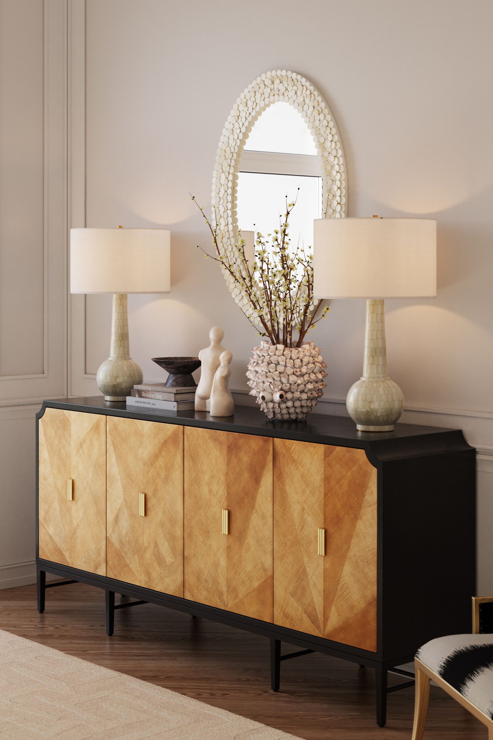 3D rendering of a styled living room vignette featuring ceramic table lamps, a gold-front sideboard with brass handles, and an oval shell-framed mirror against paneled walls